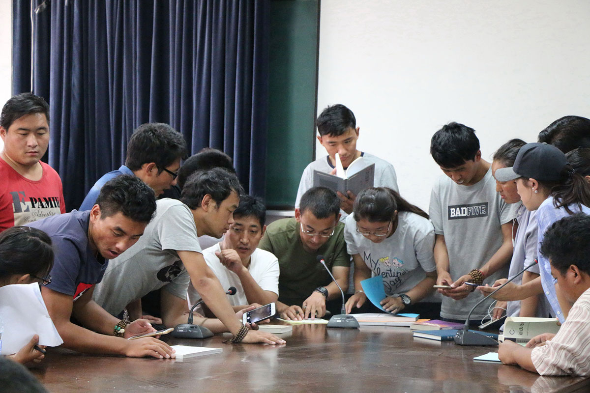 students discussing books at a classroom table.